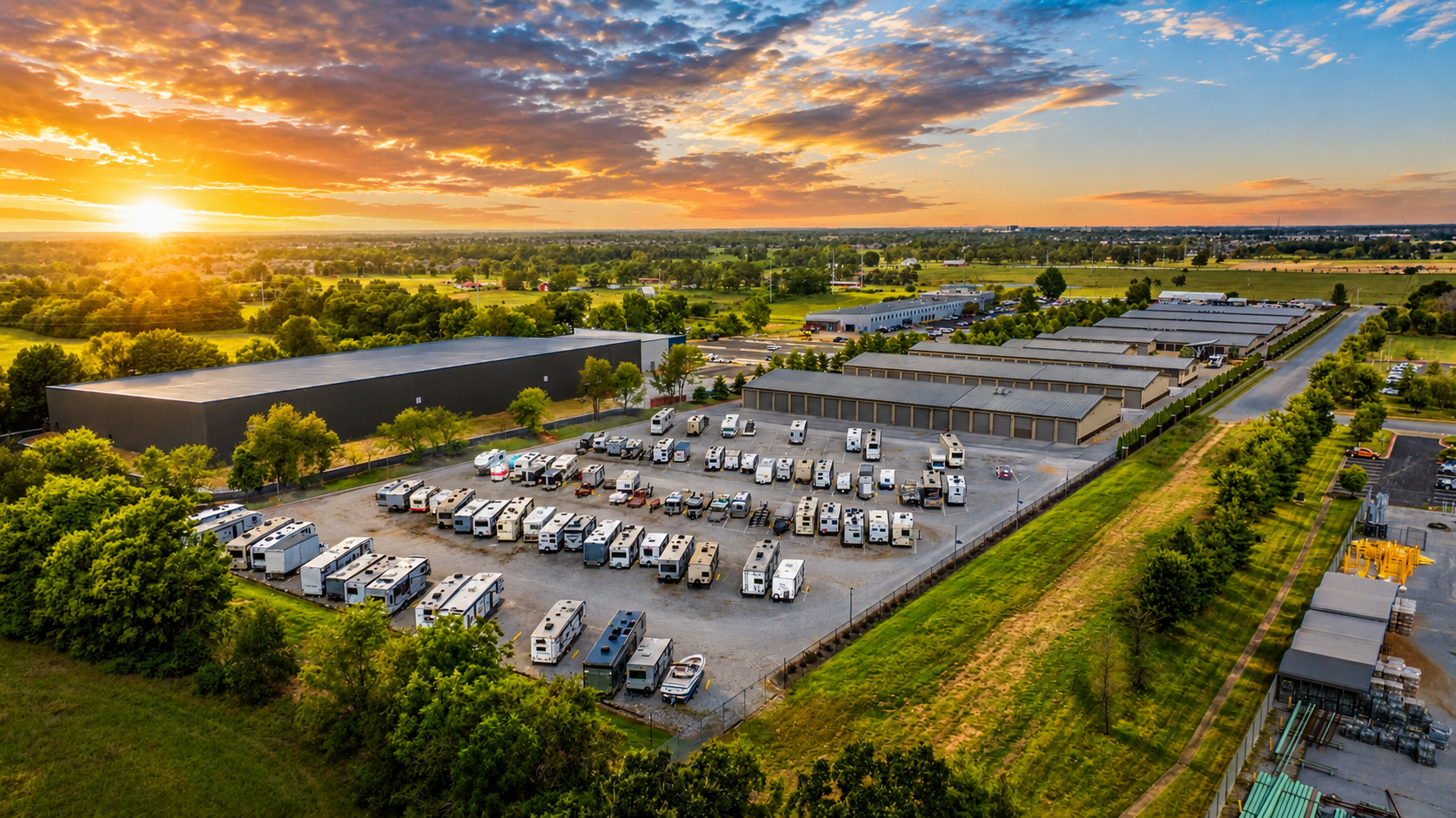 Aerial sunset view of RV and boat storage at Modern Storage® Lowell featuring outdoor parking, storage buildings, and surrounding landscape.